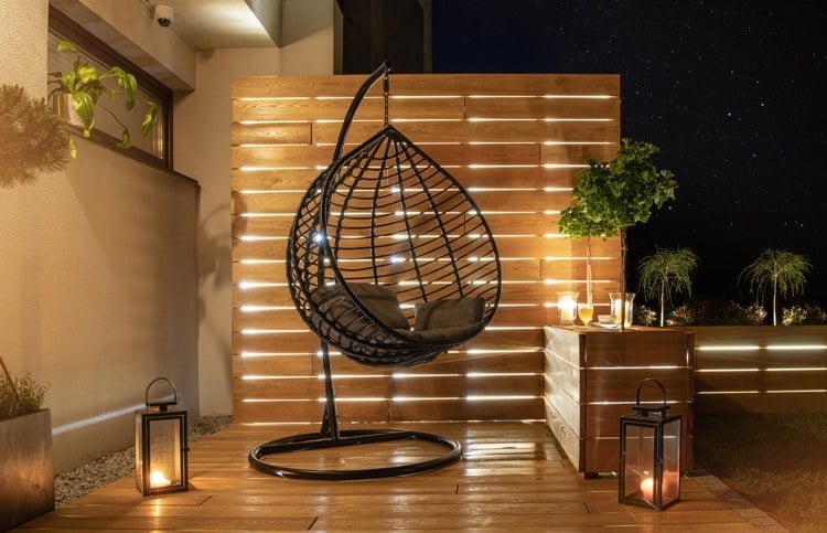 Außenbeleuchtung-für-Terrasse-mit-Kerzen-und-Wandleuchten und indirekter Beleuchtung hinter Paravent aus Holz