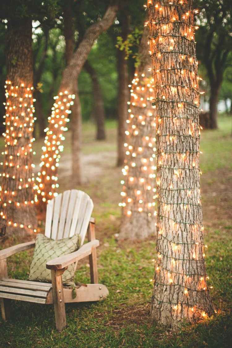 Baum dekorieren im Garten - Lichterketten um den Baumstamm wickeln