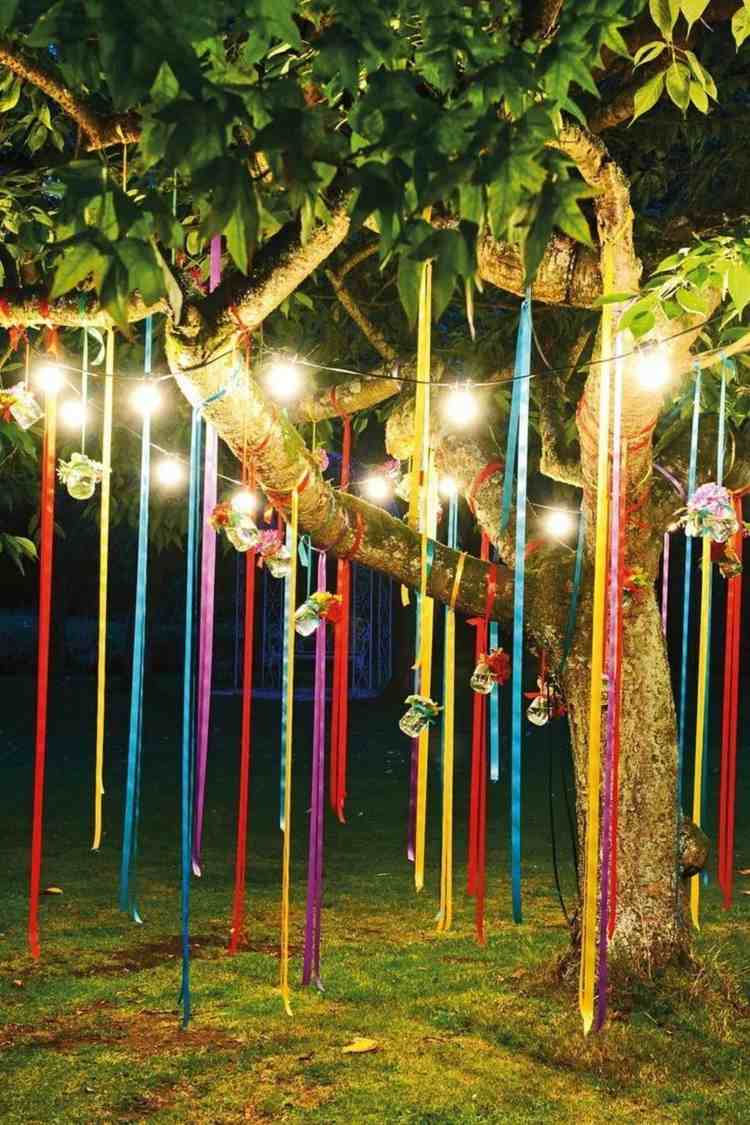 Baum dekorieren im Garten für eine Party mit bunten Bändern und Lichterkette