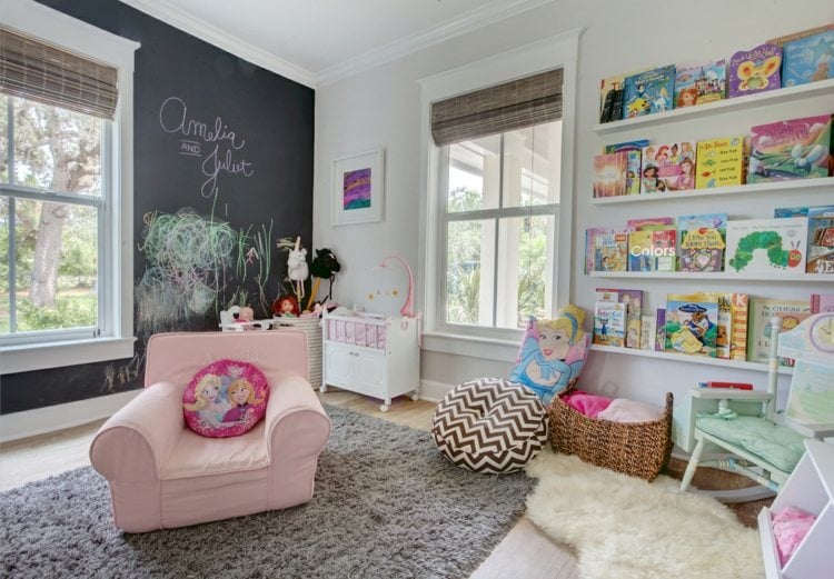 Mädchenzimmer mit Wand in Tafelfarbe und Leseecke mit vielen Büchern an der Wand