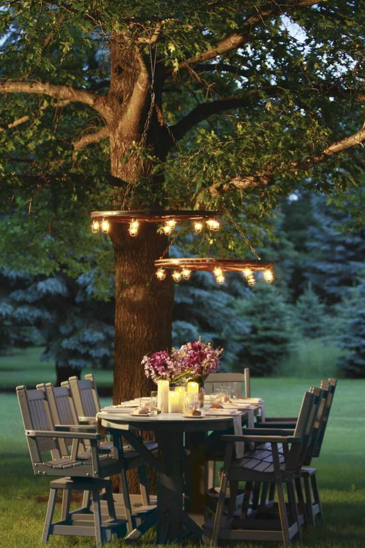 Rustikale Beleuchtung mit Holzrad über einem Esstisch unter dem Baum