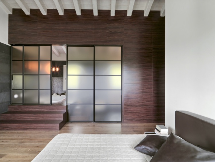 Wandpaneele aus dunklem Holz passen gut zu hellen Möbeln im Schlafzimmer