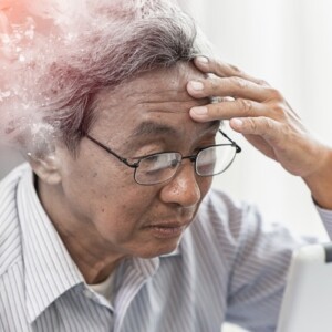 asiatischer mann vor computer beim denken dargestellt mit aktiver gehirnfunktion