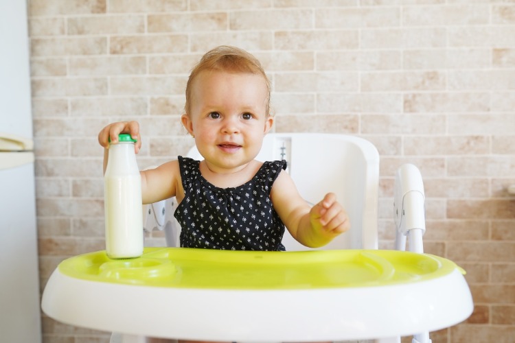 baby kleines kind im stuhl hält flasche mit muttermilch