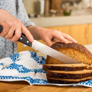 frau schneidet glutenfreies brot aufgrund von zöliakie symptome mit medikament gegen arthritis verhindern