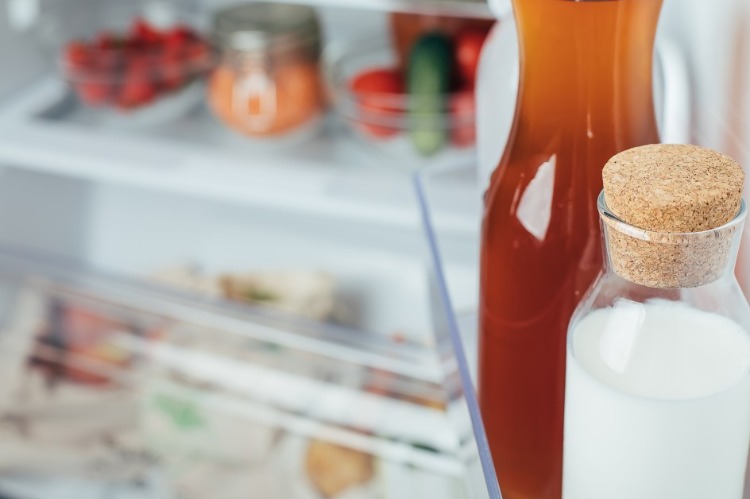 frische nicht pasteurisierte milch in flasche vor kühlregal mit gemüse