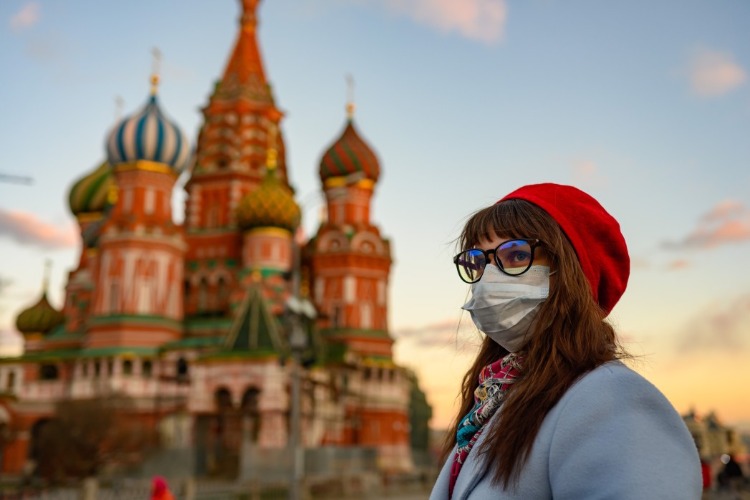 junge frau trägt schutzmaske während covid 19 pandemie mit kreml im hintergrund