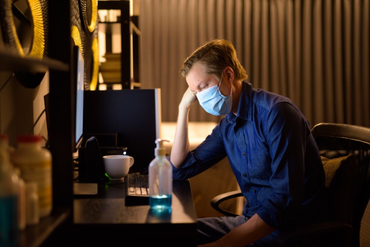 junger mann im dunklen zimmer trägt neuentwickelte schutzmaske gegen coronavirus