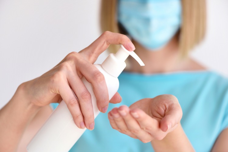 krankenschwester benutzt antiseptikum spray mit schutzmaske gegen coronavirus