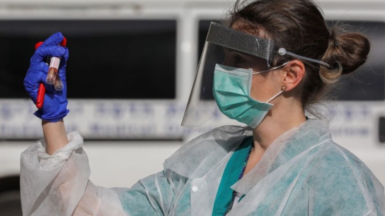 medizinische angestellte mit schutzkleidung hält blutproben zum testen von coronavirus