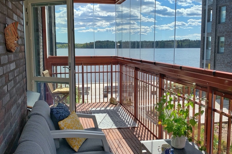 verglaster Balkon mit Holzboden und grauen Möbeln