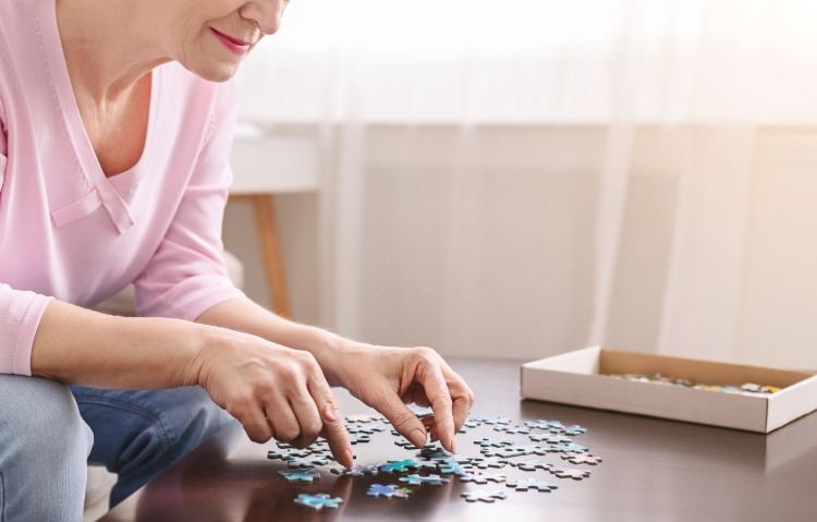 ältere frau versucht teile von puzzle anzuordnen aufgrund von demenz