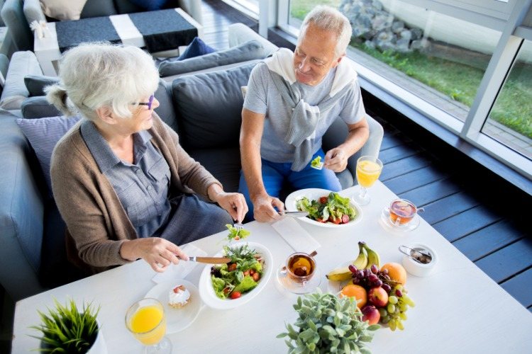 älteres paar im restaurant mit pflanzlichen lebensmitteln gesunde alterung mit diät