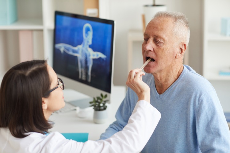 ärztin untersucht älteren patien auf symptome von coronavirus im mundhöhle