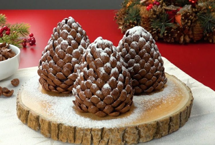 Essbare Winterdeko auf einer Holzscheibe - Zapfen mit Paste aus Erdnussbutter