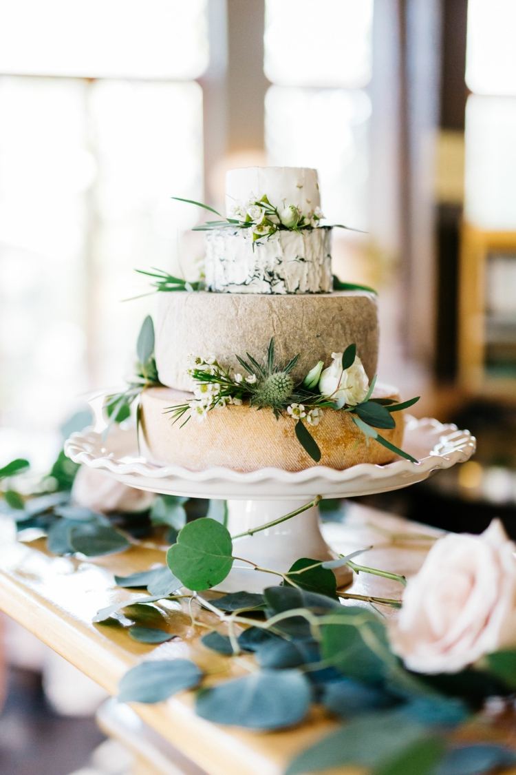 Vintage cheese wedding cake with green and white decoration made of flowers and leaves