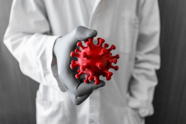 forscher hält coronavirus figur in der hand