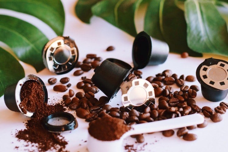 capsules with coffee beans and green plant leaves