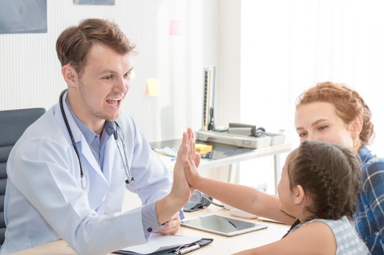 pediatrician clapping with little patient and her mother