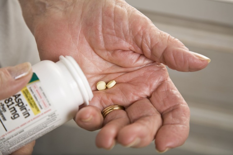 senior woman takes two tablets of aspirin