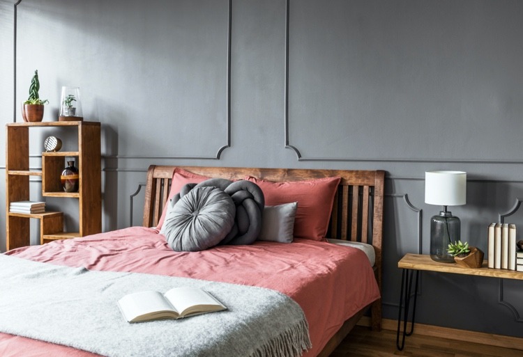 Massivholzbett dunkel gegen eine graue Wand im Schlafzimmer