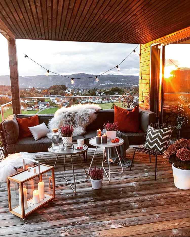 Decorate the terrace in autumn with decorative cushions in brick red and candlelight