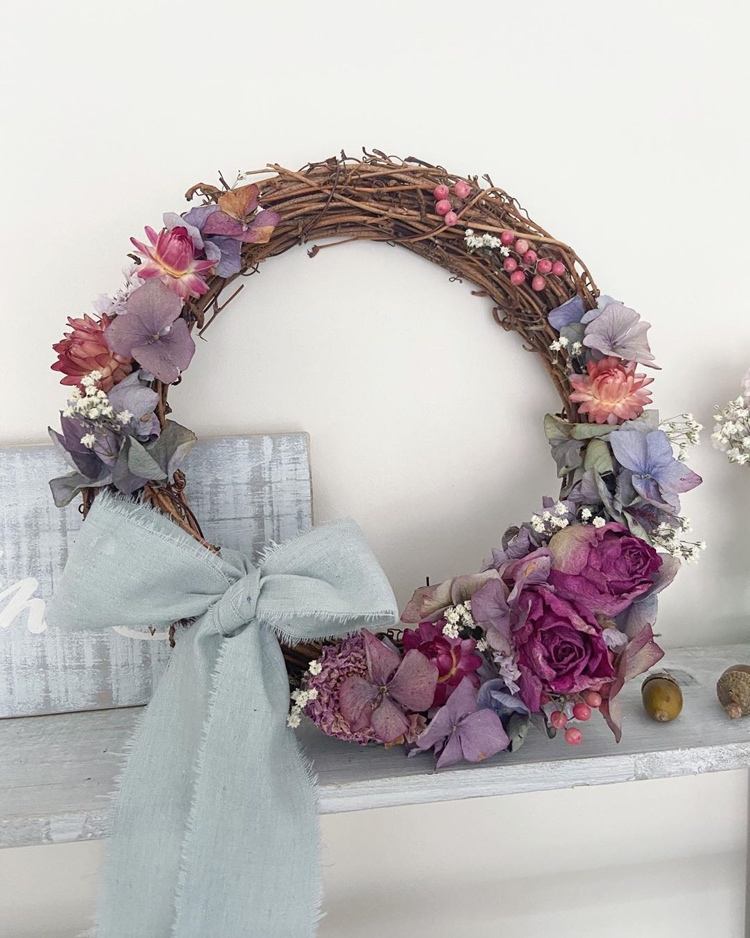 Willow wreath decorated with dried flowers in shades of purple