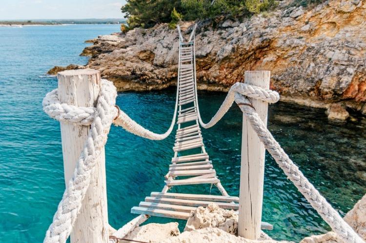 alte holzbrücke in weiß verbindet felsen mit der stadt pula in kroatien als sehenswürdigkeit und reiseziele im herbst