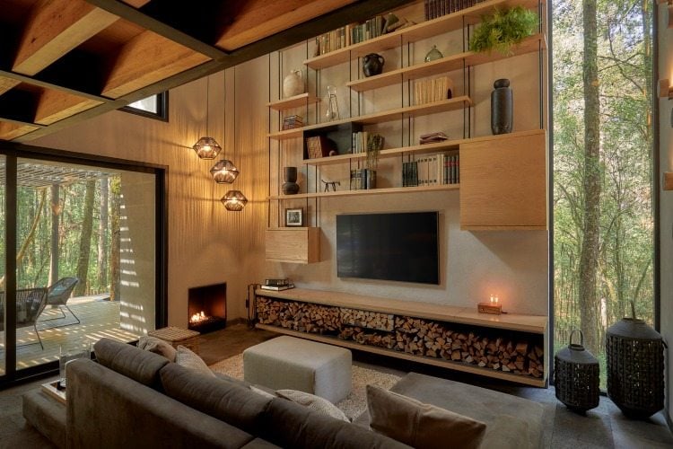 dezent eingerichtetes wohnzimmer mit wandregal und flachbildfernseher über brennhölzern