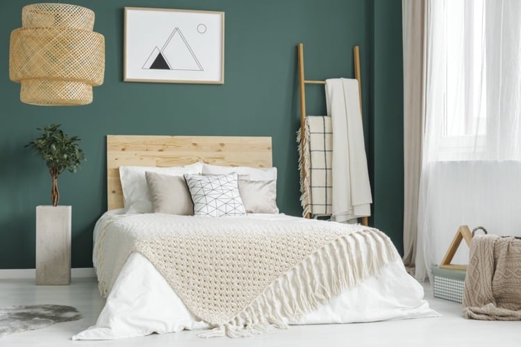 eine dunkelgrüne Wand im Schlafzimmer hebt das Zirbenholzbett schön hervor