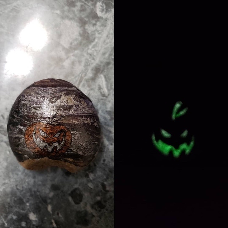 im Dunkeln leuchtender Kürbis auf Stein zu Halloween