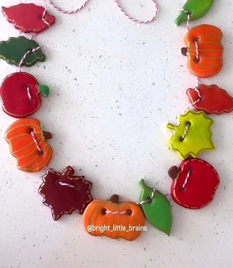 Kürbisse, Äpfel und Blätter als Anhänger für eine Herbstgirlande