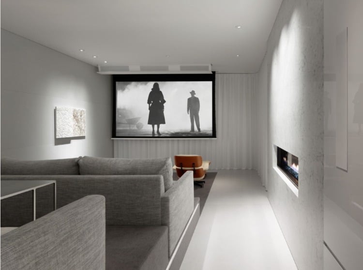 minimalistischer kinoraum mit eingebautem kamin und sitzgelegenheiten in grauen farbtönen