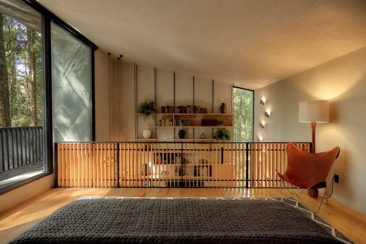 minimalistisches design im obergeschoss von waldhütte mit lichtdurchlässigen fenstern und balkon