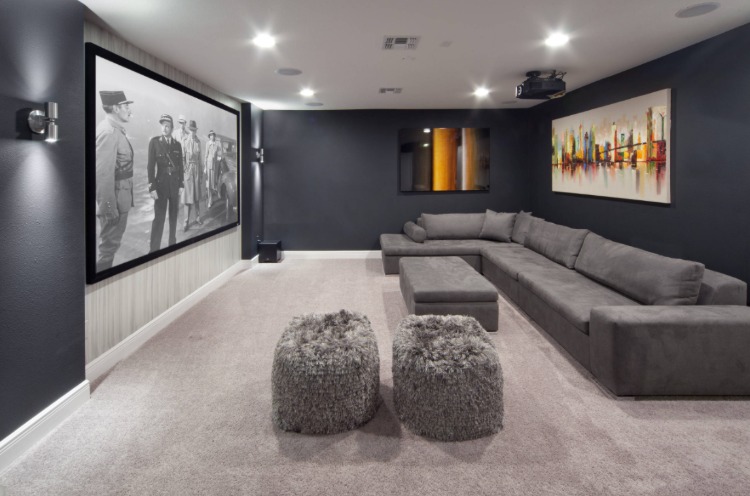 mit teppichboden verkleidetes heimkino wohnzimmer mit großer leinwand und langem sofa in grau