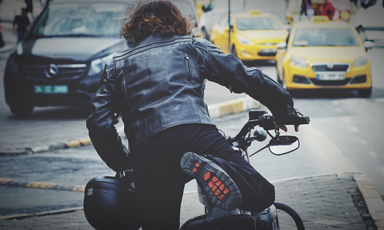 motorradfahrer mit motorradjacke steigt auf sein motorrad auf der straße