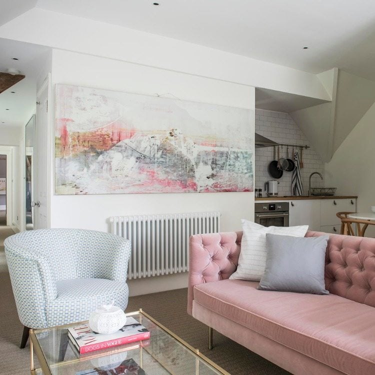schönes wohnzimmer mit rosafarbener couch und großem bild über heizkörper säubern und entstauben