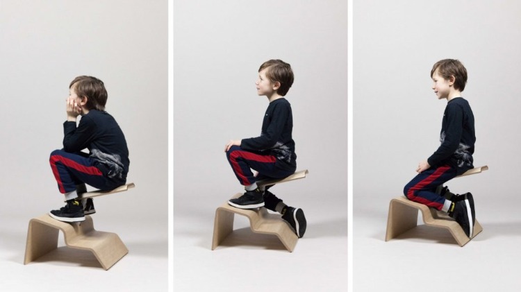 schüler wechselt seine sitzhaltung auf einem speziell dafür entworfenen sitz aus holz