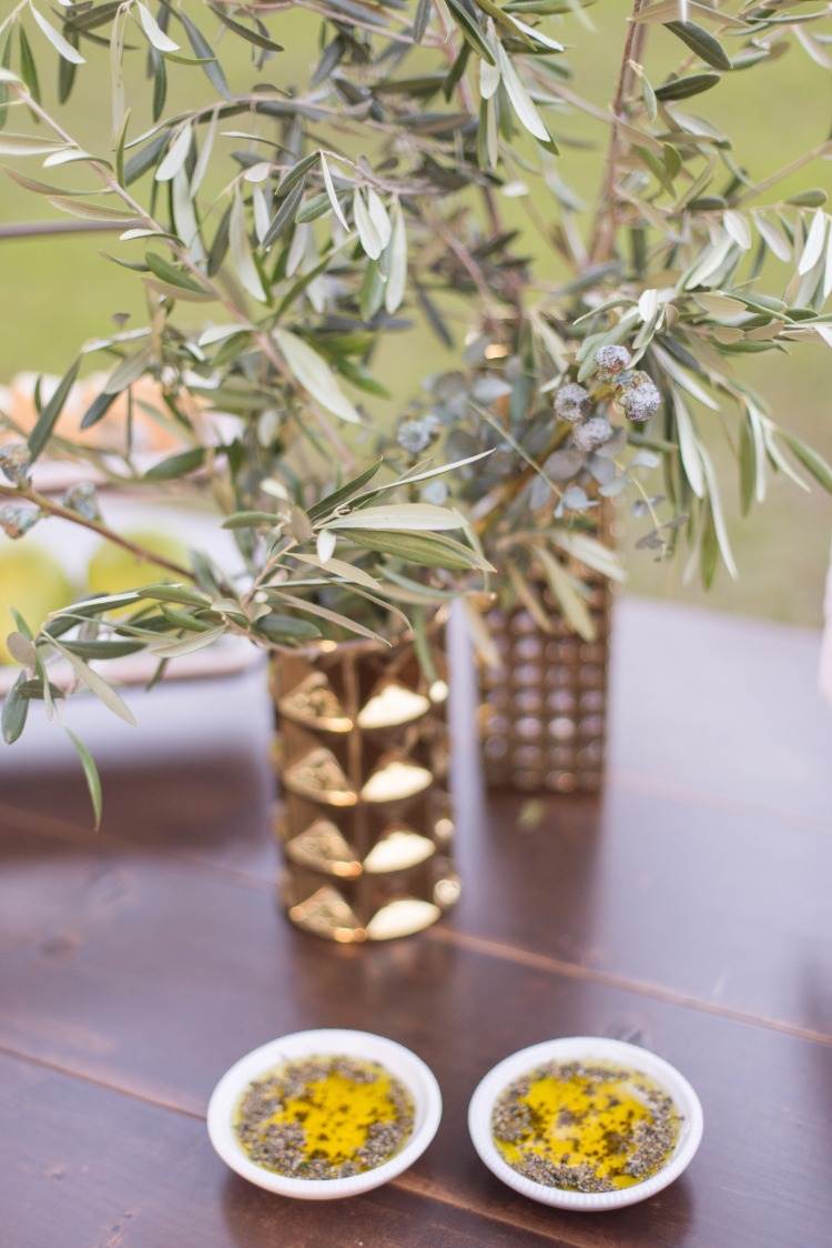 trockene baumzweige in vasen neben olivenblattextrakt mit kräutern in kleinen schüsseln