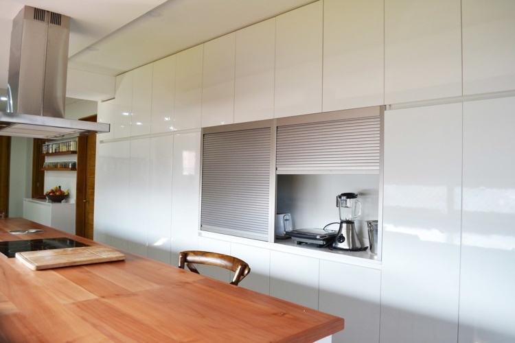 white high-gloss kitchen with handleless fronts and tambour door system