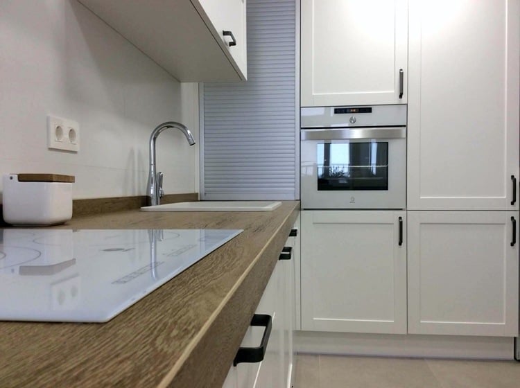 white kitchen with black handles, wooden worktop and aluminum roller shutter system