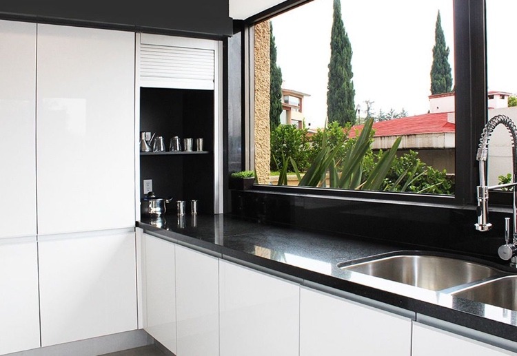 white kitchen with black worktop and sink in front of the window