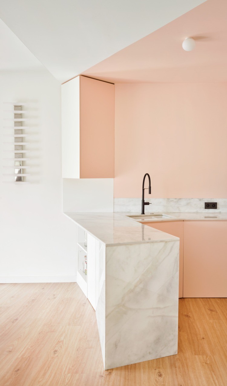 kontrastierender wasserhahn in schwarz und küchenarbeitsplatte aus marmor in weiß unter hellrosa wänden