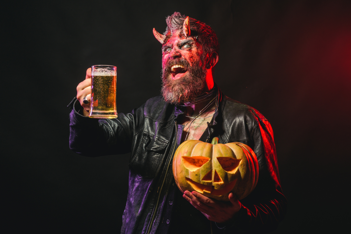 mann mit bart und halloween make up, der einen kürbis und einen bären hält