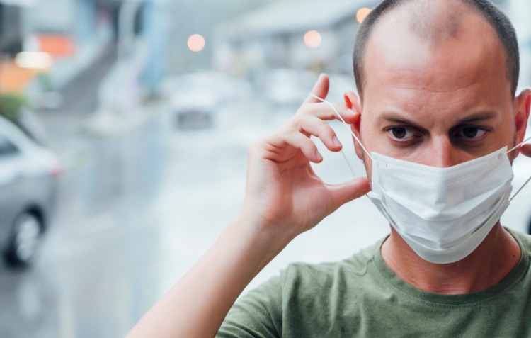 mann setzt eine schutzmaske während pandemie auf sein gesicht
