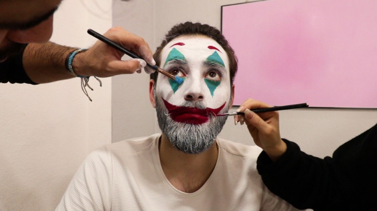 visagisten schminken gesicht von bärtigem mann als clown