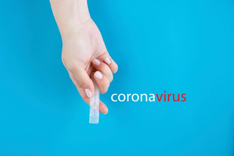 weibliche hand mit maniküre hält arzneimittel neben coronavirus aufschrift auf blauem hintergrund