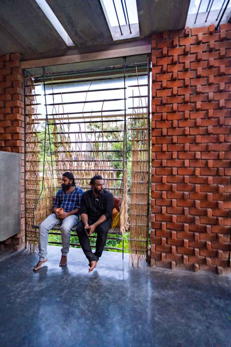 zwei architekten des architektenbüros wallmakers sitzen auf einer schaukel im neulich gebauten haus mit backsteinwand innen