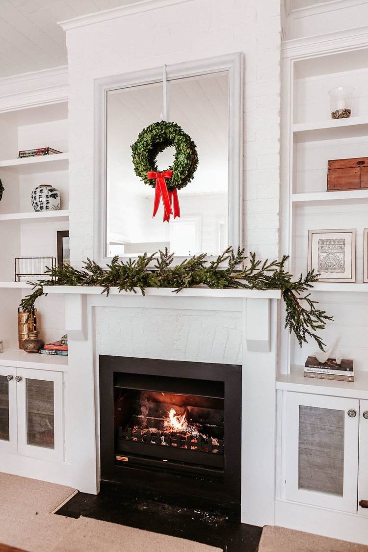 Kaminsims minimalistisch zu Weihnachten dekoriert mit Tannenzweigen und Buchsbaum-Kranz