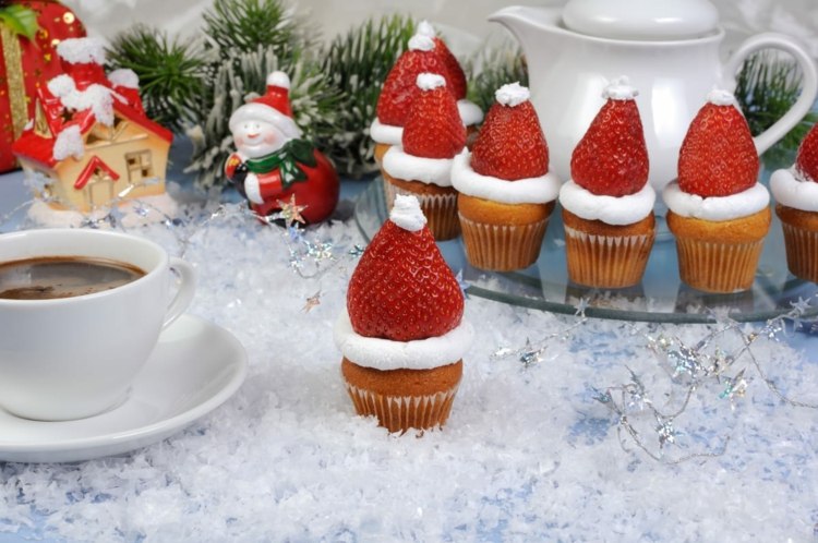 Muffins oder Cupcakes mit Frosting und Erdbeere in Weihnachtsmann-Optik